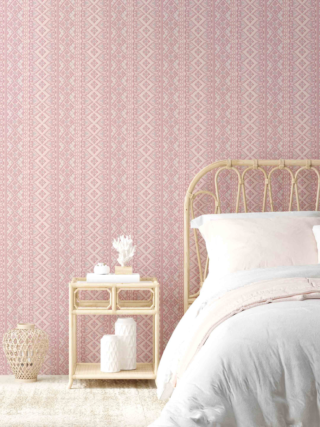 A wall adorned with berry pink wallpaper featuring an intricate geometric pattern, in a bedroom setting with a bed, nightstand, and decorative items.