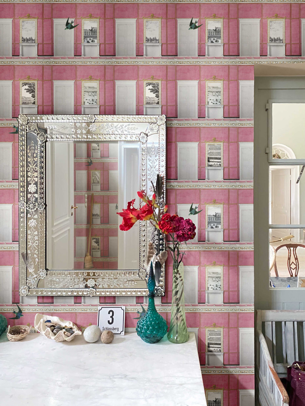 Decorative mirror on a table with pink whimsical patterned wallpaper