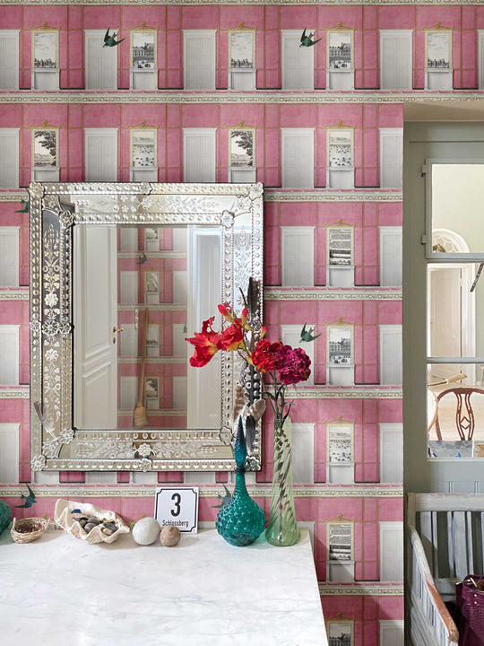 Decorative mirror on a table with pink whimsical patterned wallpaper