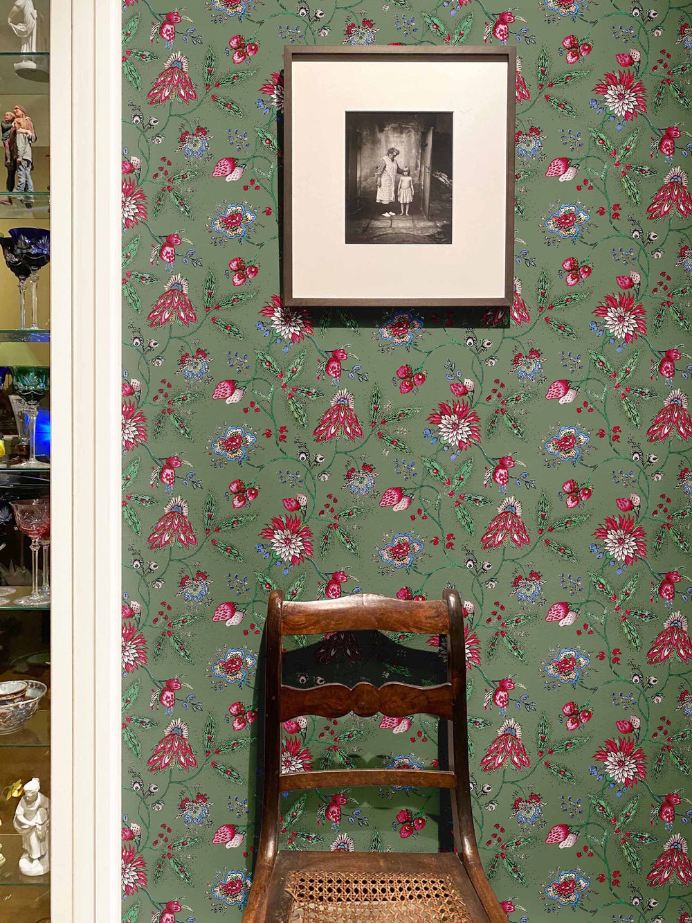 Green floral wallpaper with pink and blue flowers on the wall of a dining room by Milola Design