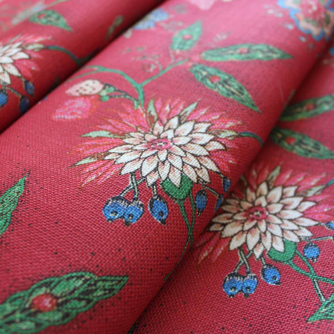 Close-up of Amalita Floral Fabric in Fuchsia Red featuring colorful flowers and leaves on a textured red background.