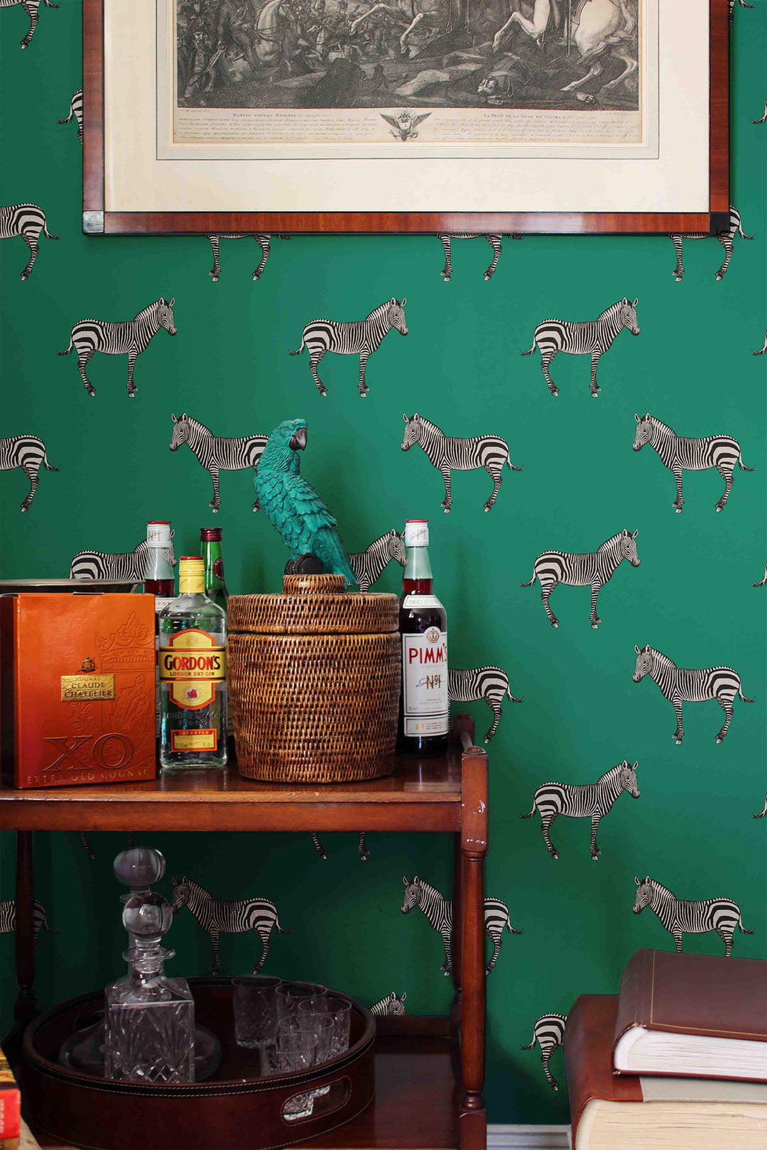 Green wallpaper with zebra pattern, wooden table with drinks and decor, framed picture above.