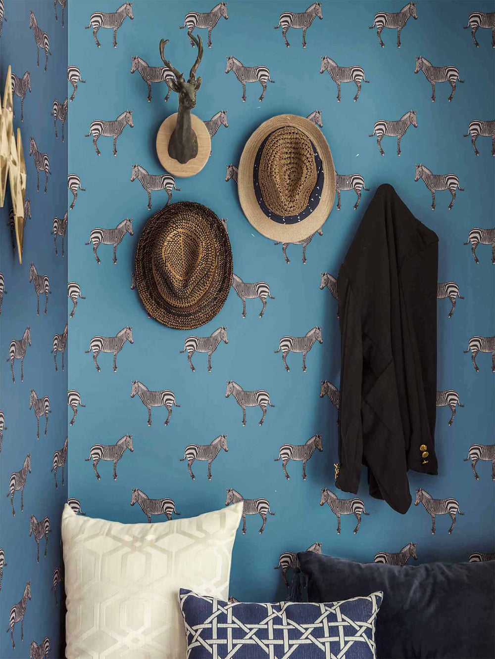 Wall with blue wallpaper featuring zebra pattern, decorated with hats and a coat.