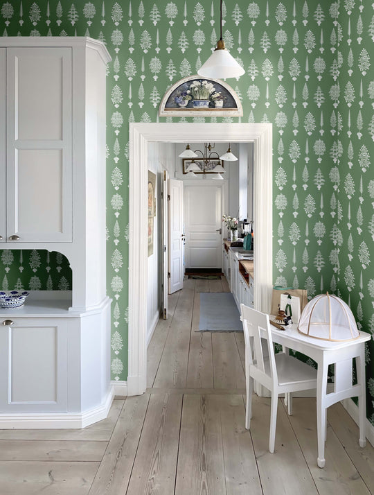 An image of a kitchen wall decorated with a green and white botanical wallpaper by Milola Design