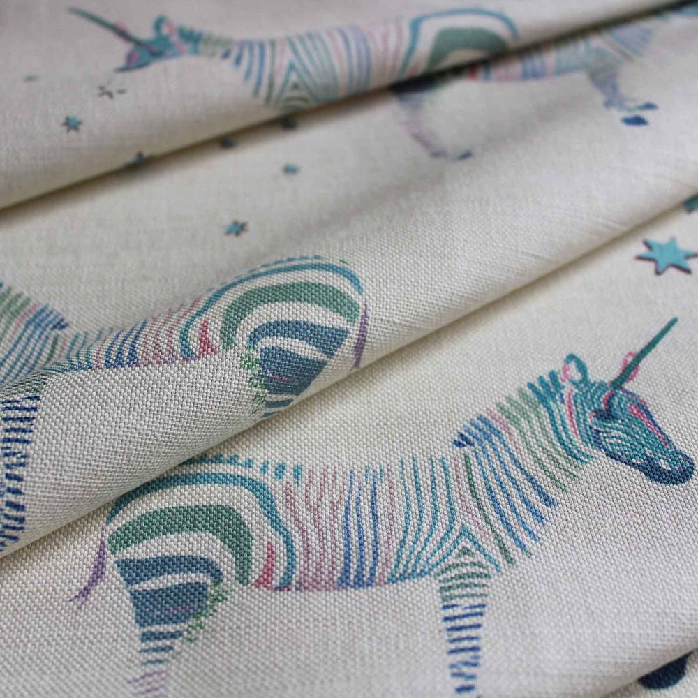 A printed curtain fabric featuring rainbow coloured unicorns with zebra stripes perfect for kids bedrooms as curtains or blinds by Milola Design.