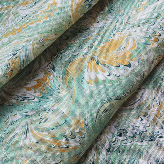 A soft green marbled printed fabric with marblized swirls of yellow, dark blue and white. Suitable fabric for curtains, Blinds and sift furnishings