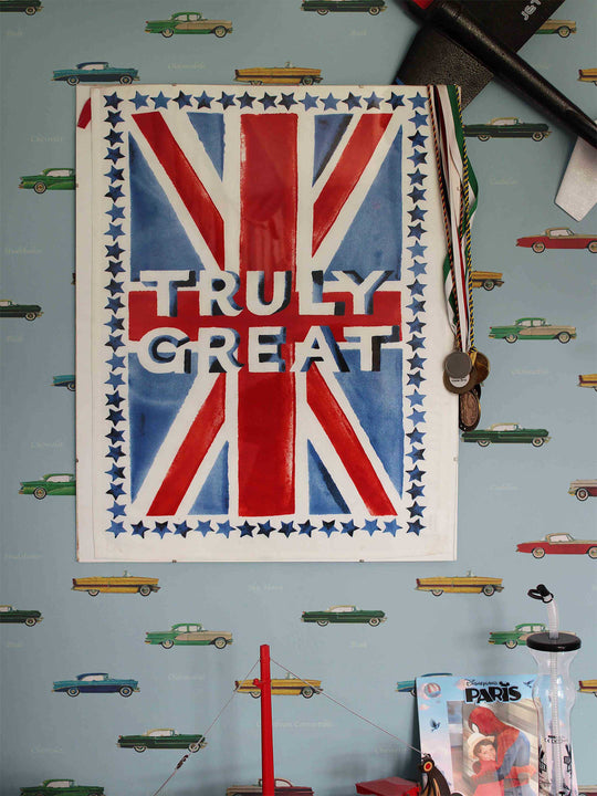 A wallpaper featuring vintage car illustrations and a poster with text 'TRULY GREAT' on a background resembling a British flag pattern, displayed in a child's bedroom.