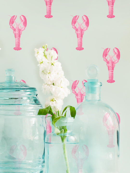 A pink lobster wallpaper on wall behind glass bottles by Milola Design
